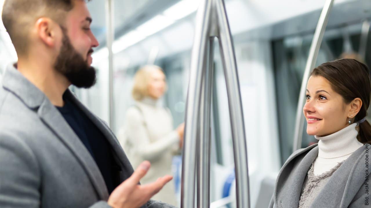 Kürzeste Flirt Anleitung für Männer. Mann flirtet in einem öffentlichen Verkehrsmittel mit einer Frau.